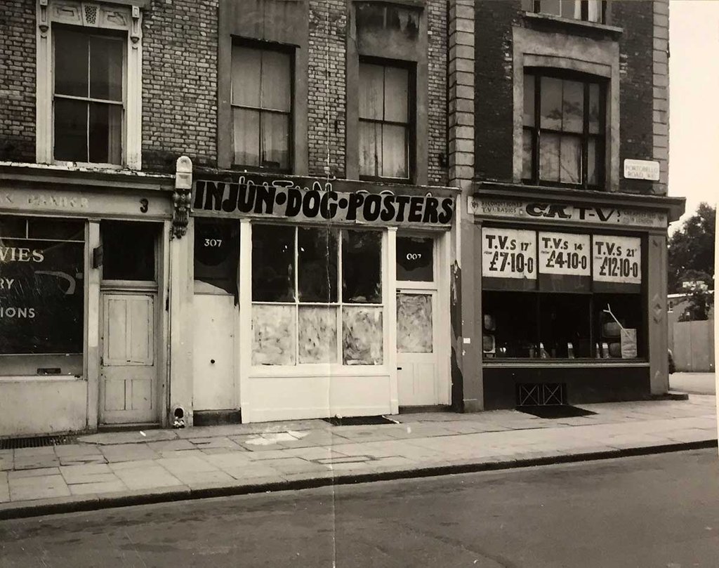 Three shops with flats above. The shop at number 307 has a sign saying 'Injun Dog Posters'.