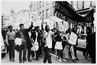 A black and white photograph of peaceful group of protestors were followed by many police officers.