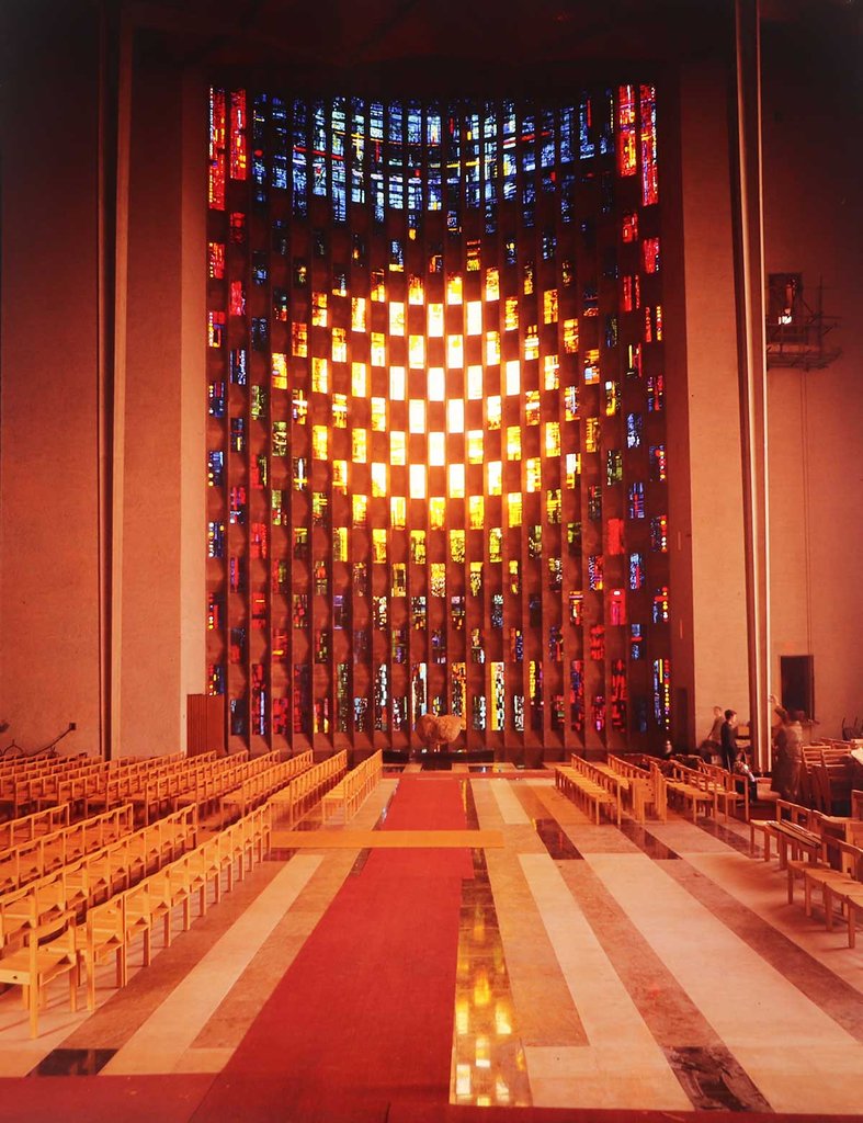 A photograph of a large modern stained glass window in an abstract grid design