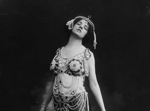 A photograph Allan dressed as Salome. She wears a beaded cropped top and translucent skirt