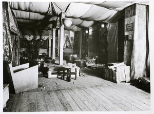 The interior of a club with no people. It is full of soft furnishings, tables and draped fabric