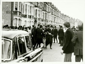 A black and white photograph of protestors being restrained by police officers