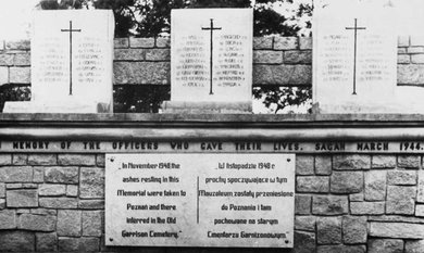 Three rectangular stones with many names and one large cross carved into each above a plaque.